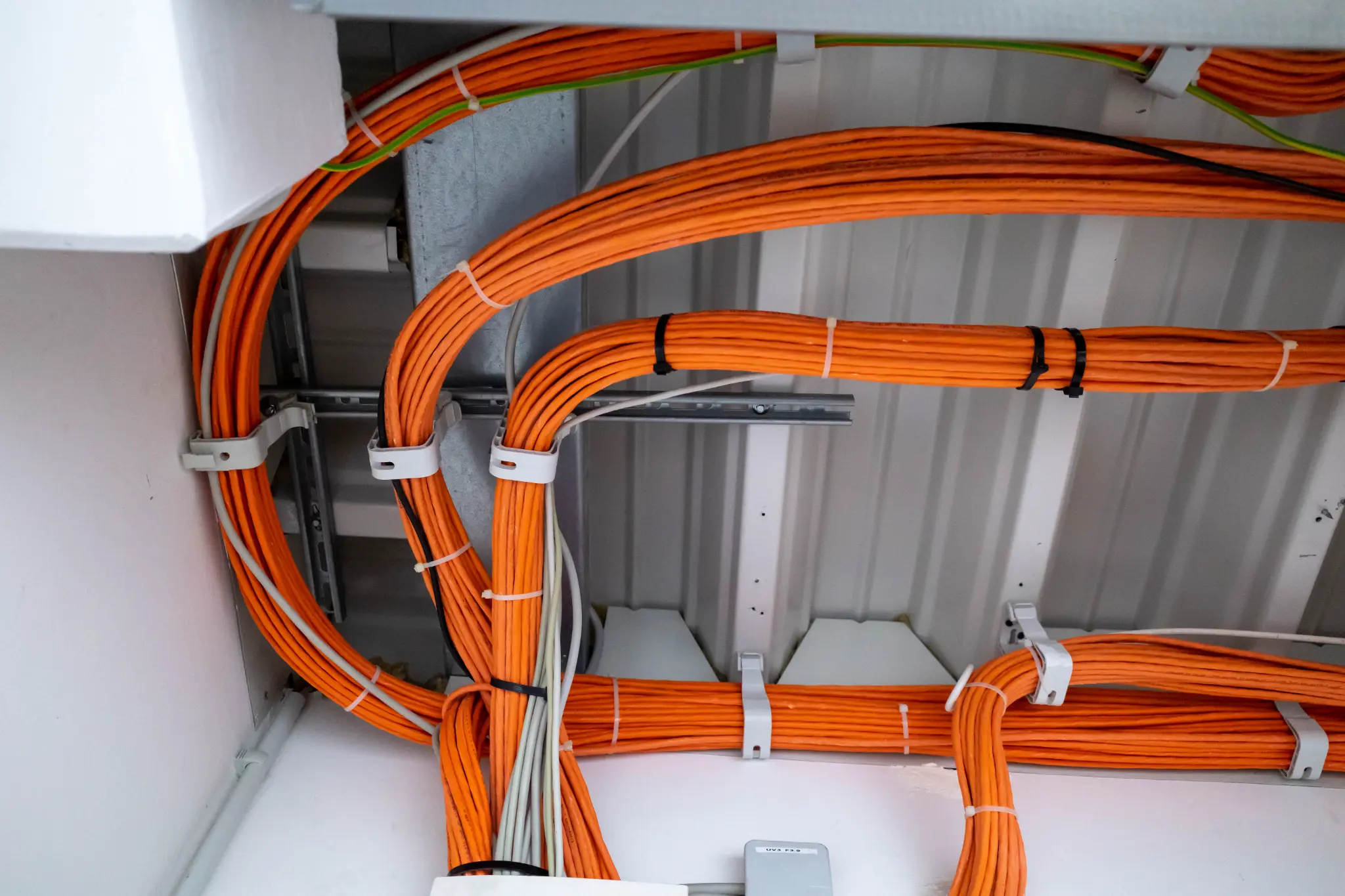 Organized orange data cabling properly managed and routed back to base in commercial building Melbourne