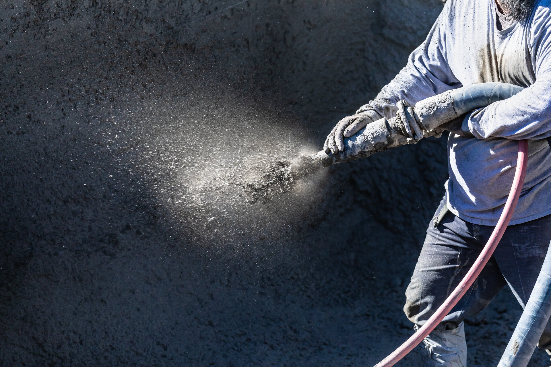 A skilled worker applying shotcrete to a concrete wall, a key process in large-scale structural repair and remediation