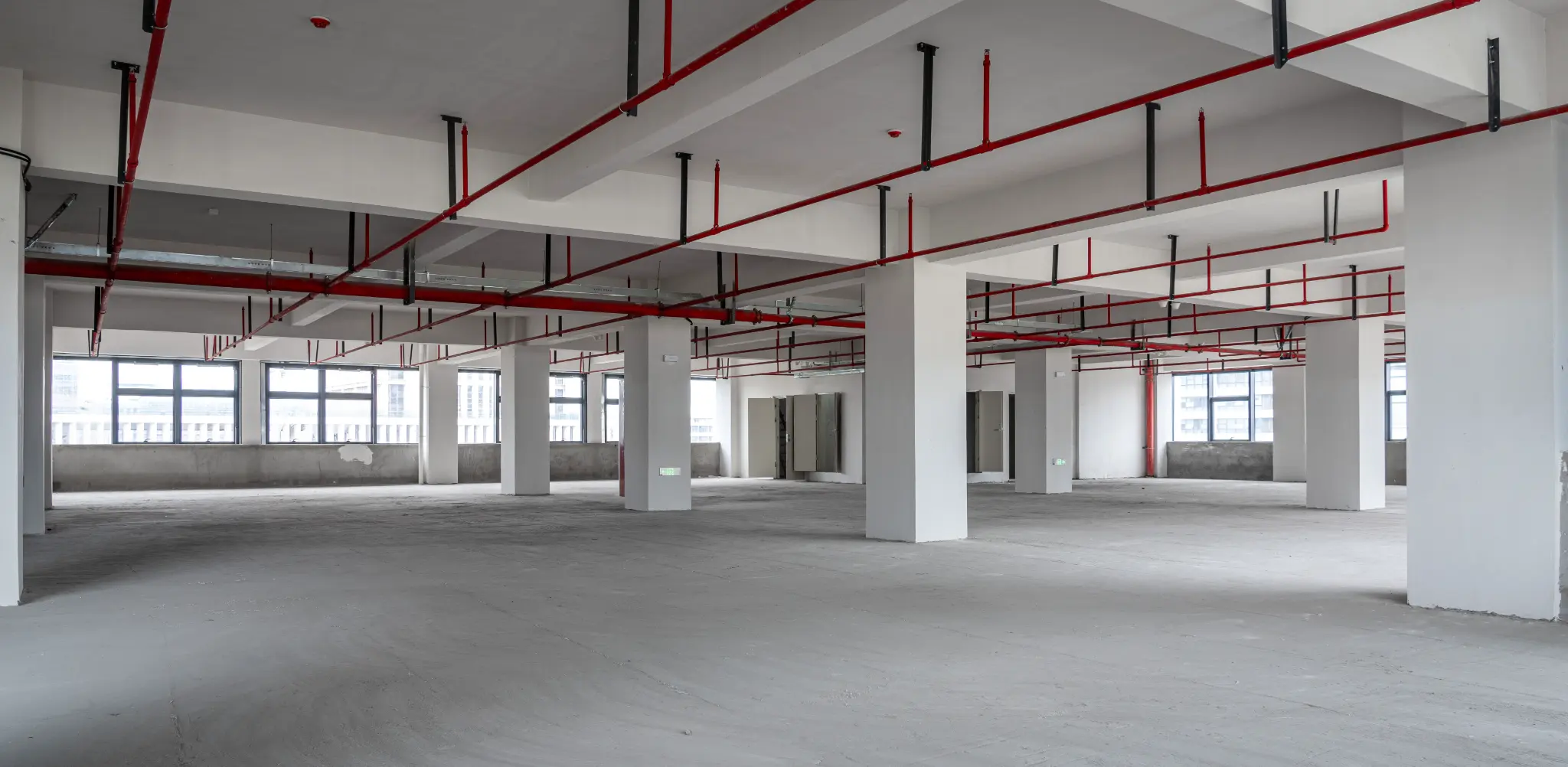 Empty commercial warehouse space after demolition and strip out in Melbourne, showing clean concrete floor and exposed ceiling services