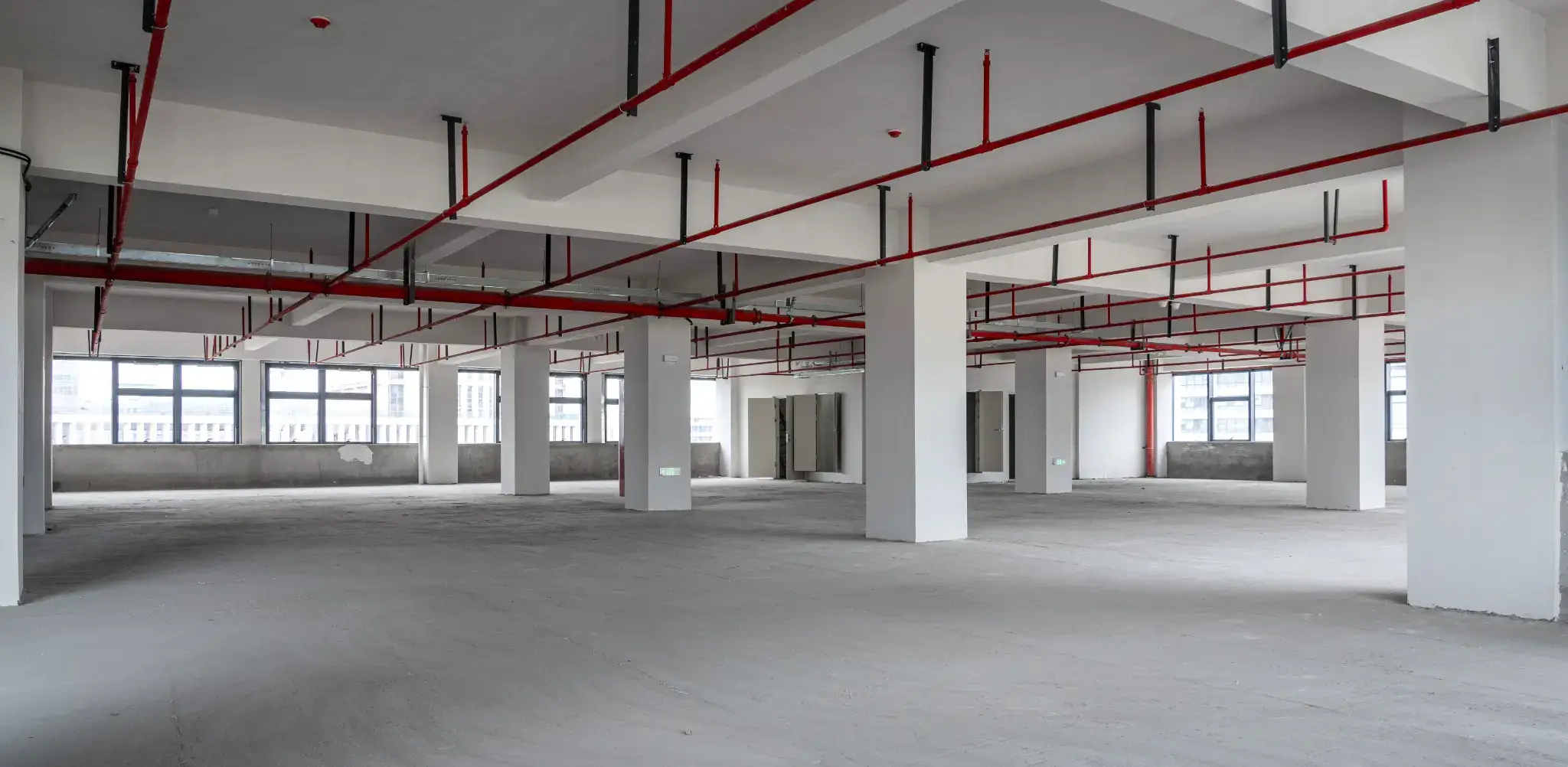 Empty commercial warehouse space after demolition and strip out in Melbourne, showing clean concrete floor and exposed ceiling services