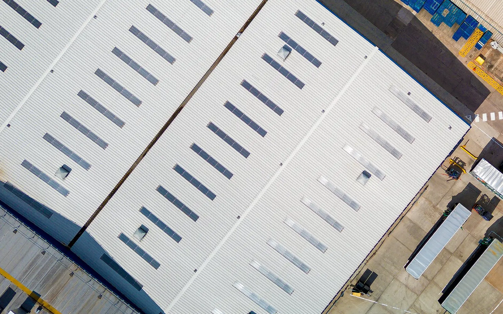 Aerial view of commercial warehouse roofs with skylights and loading yard