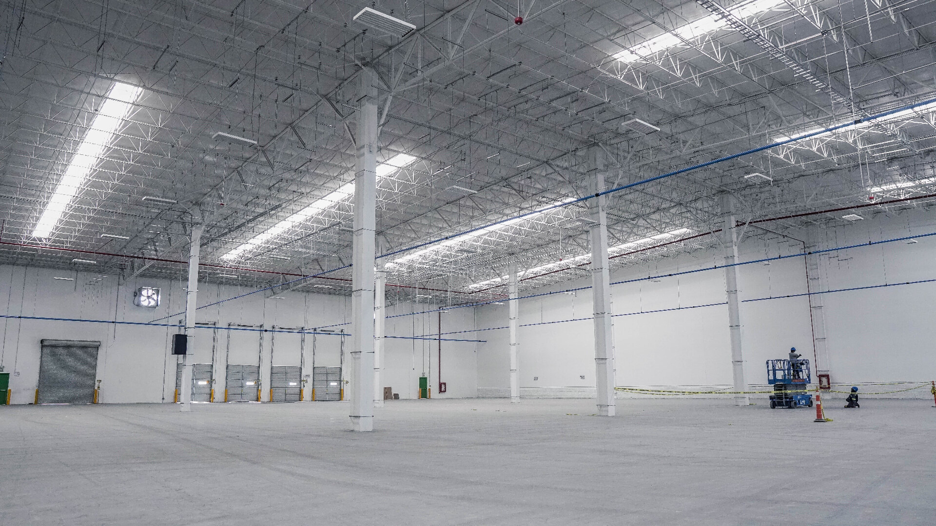 Large commercial warehouse interior with freshly painted white walls and steel structure during end of lease make good works in Melbourne