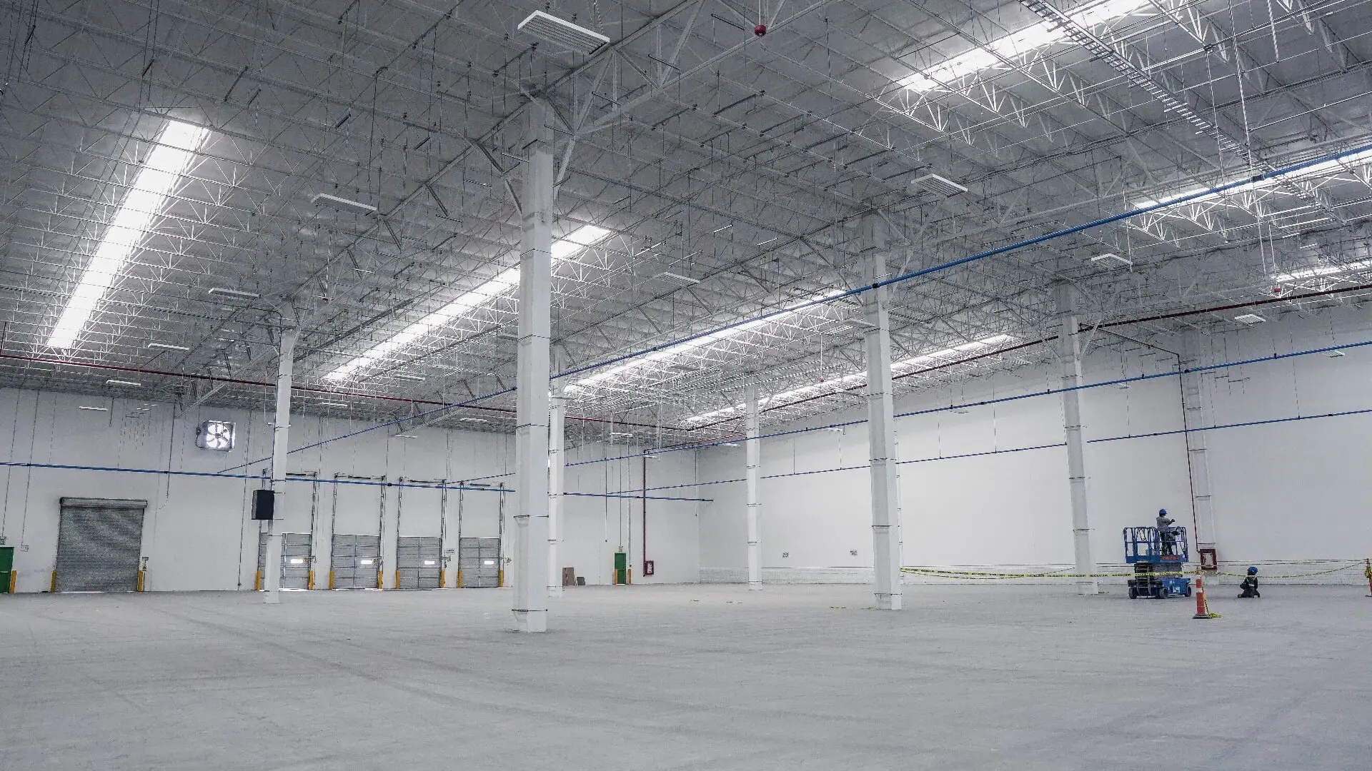 Large commercial warehouse interior with freshly painted white walls and steel structure during end of lease make good works in Melbourne
