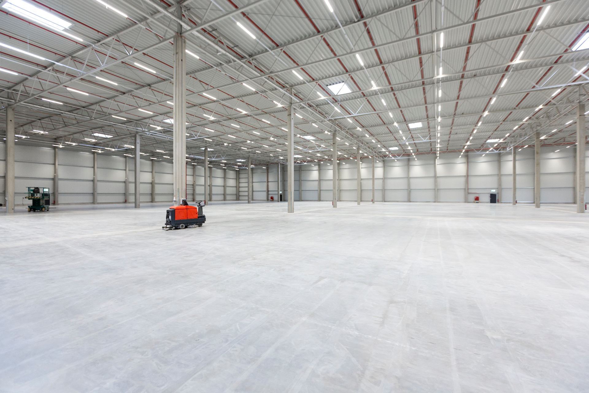 Large industrial warehouse with restored concrete slab floor and ride-on floor scrubber showing completed make good handover Melbourne