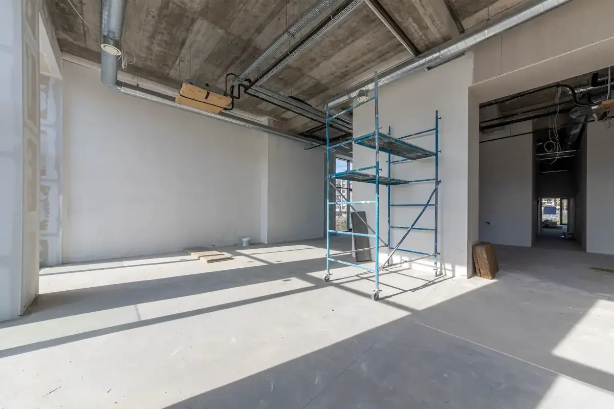 Empty commercial tenancy with scaffolding and exposed concrete ceiling during make good works in Melbourne