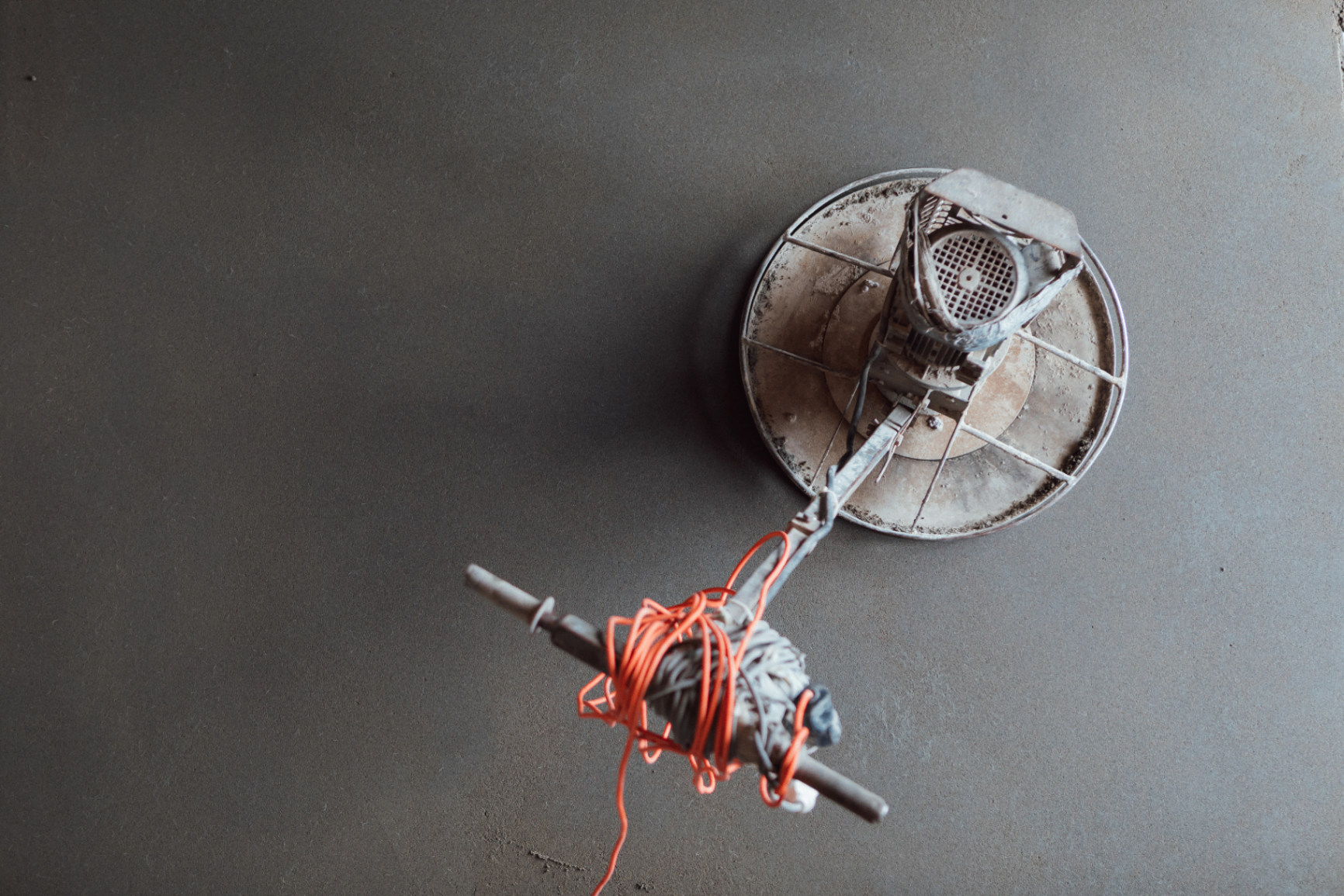 Industrial concrete power trowel with protective cage and orange power cord on warehouse floor Melbourne
