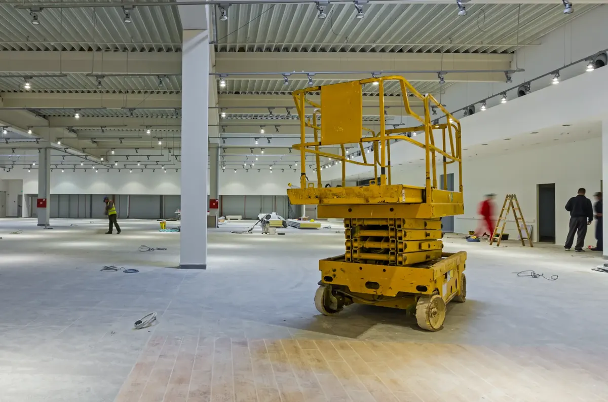 Commercial building interior undergoing strip out and make good works with scissor lift and construction workers in Melbourne