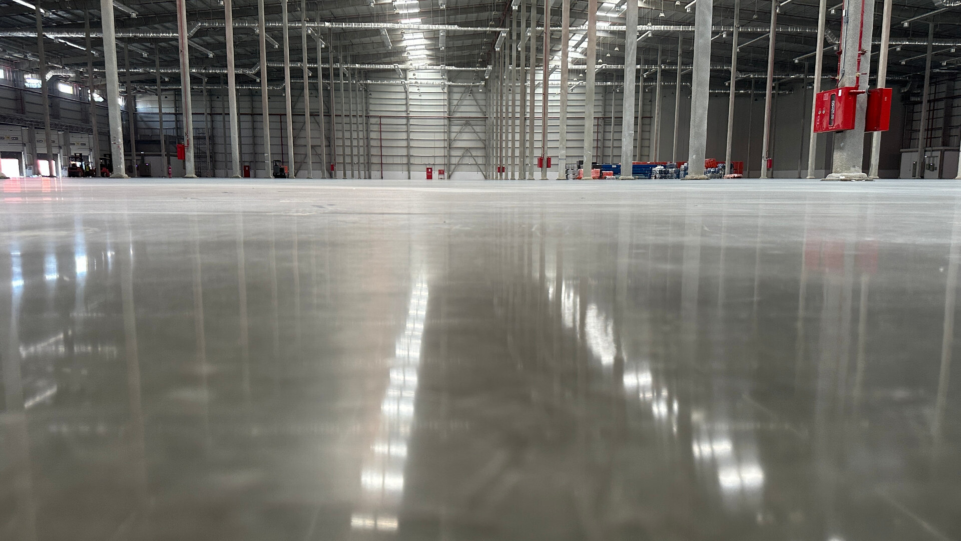 Polished epoxy floor coating in large industrial warehouse with reflective finish Melbourne