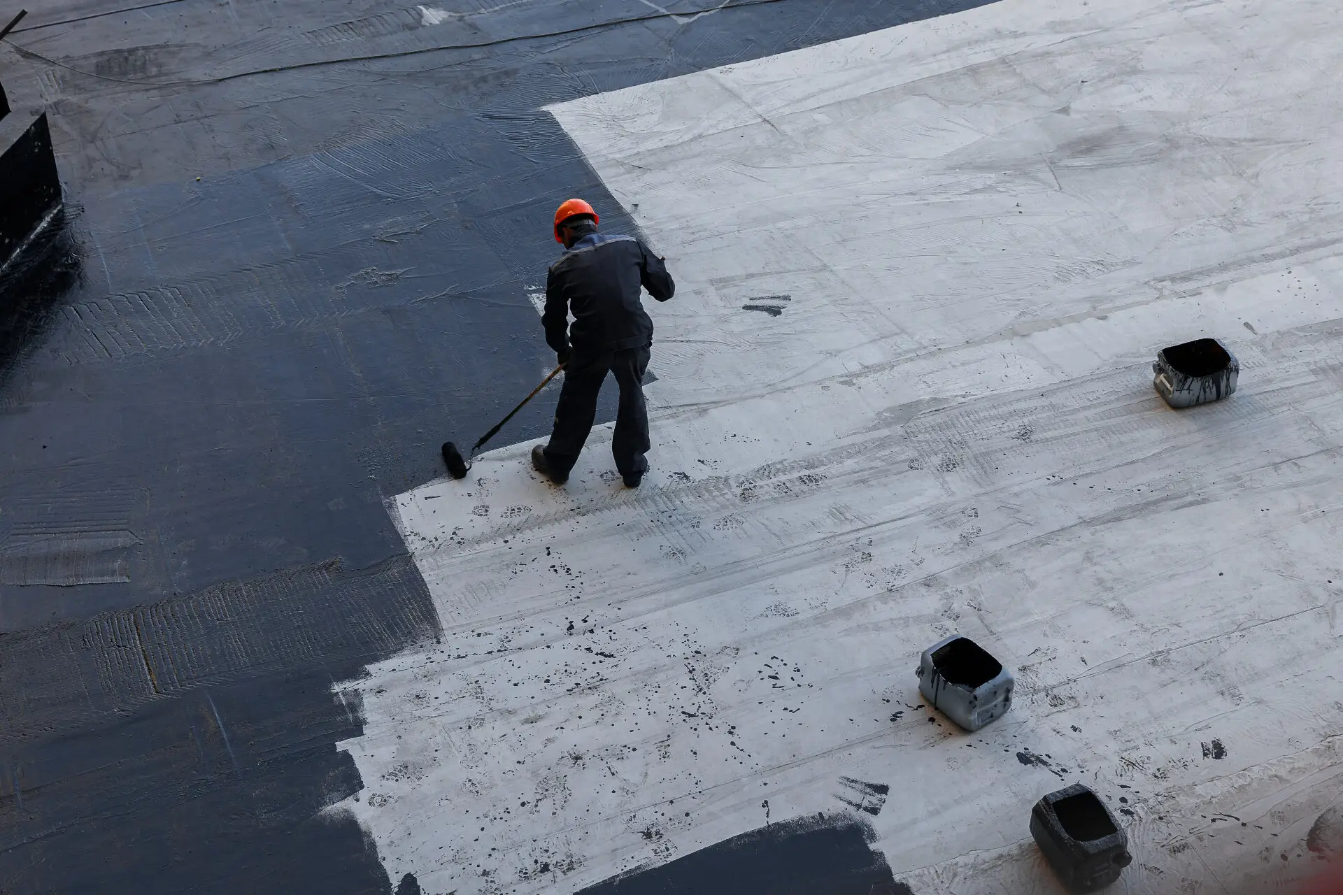 Worker applying waterproofing membrane to commercial rooftop in Melbourne