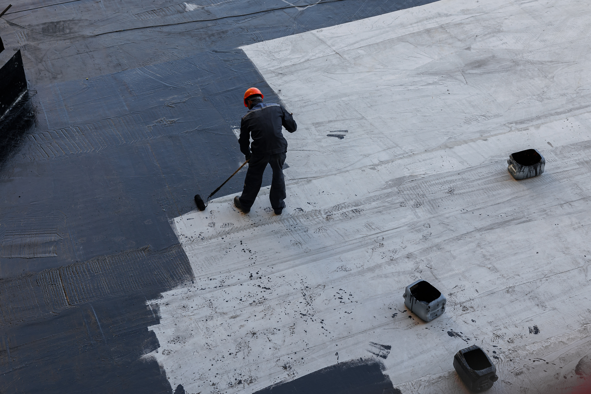 Worker applying waterproofing membrane to commercial rooftop in Melbourne