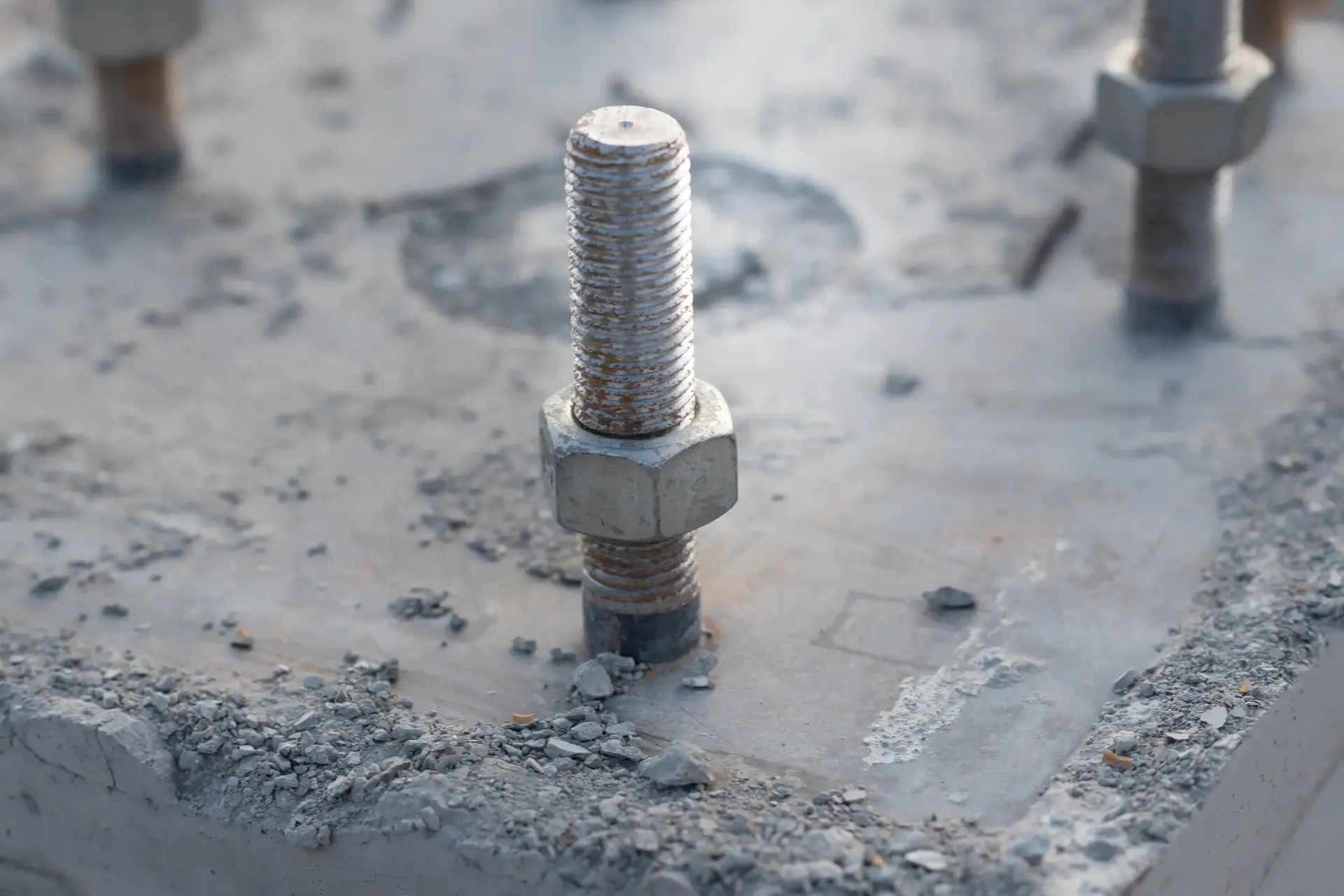 Close-up of a dynatbolt anchor protruding from a concrete warehouse floor slab with debris around the base plate prior to removal during a warehouse make good in Melbourne