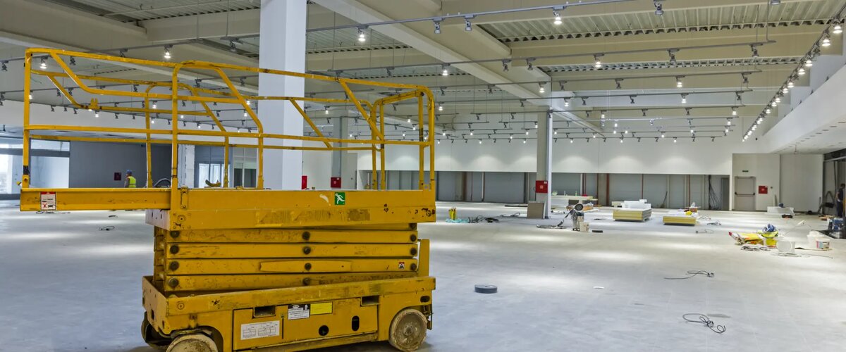 Commercial warehouse remediation works showing yellow scissor lift and concrete flooring during building rectification in Melbourne
